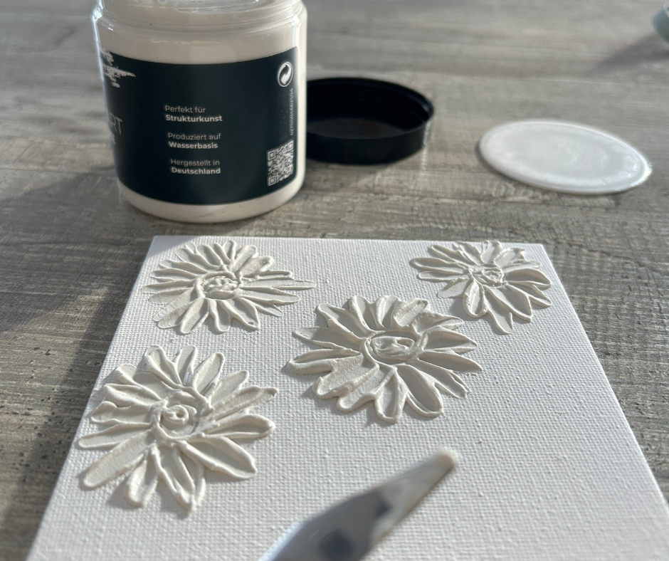 Eine Leinwand, auf der Blumen mit Strukturpaste aufgetragen sind