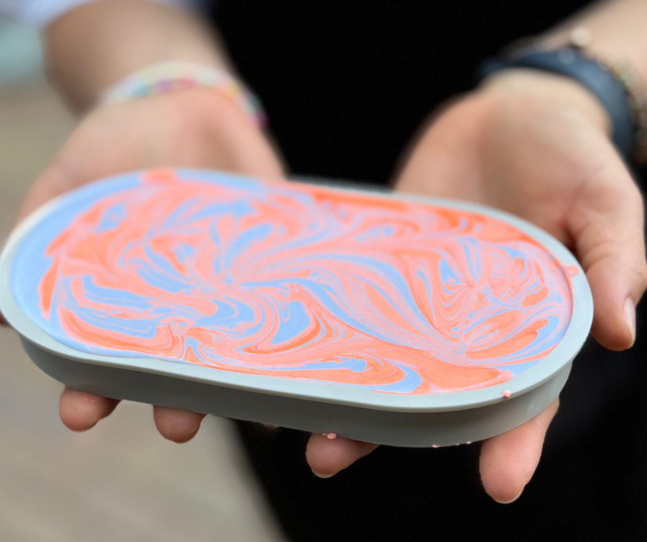 Hände, die eine Silikonform mit Kaltkeramikmasse darin halten