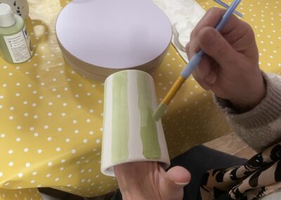 Frau bemalt Tasse mit Streifen, Keramik bemalen mit Herz