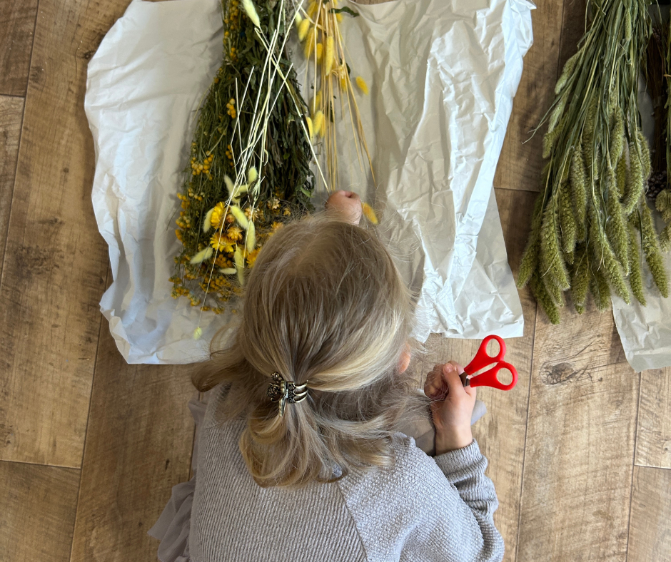 Ein Kind von oben, das gerade Trockenblumen aussucht