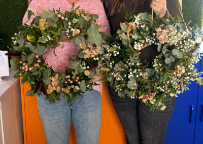 zwei Frauen halten Blumenkränze hoch