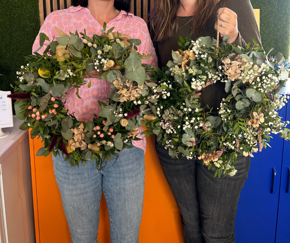zwei Frauen halten Blumenkränze hoch